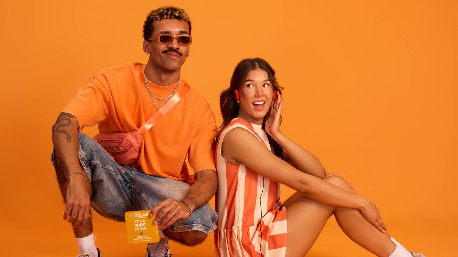 Two people sitting on an orange background